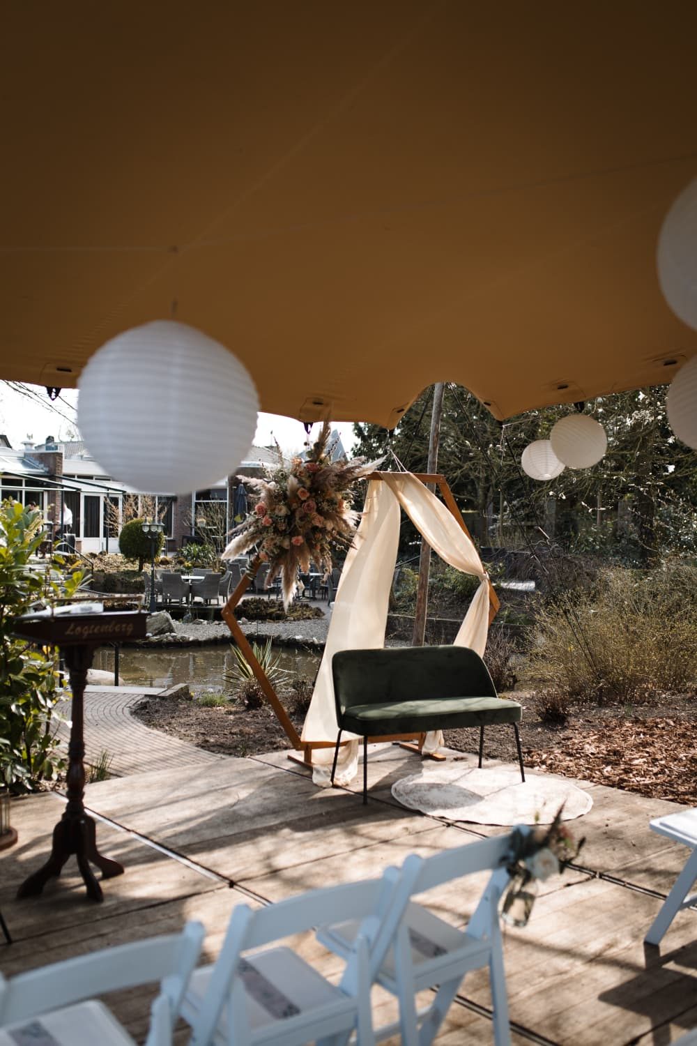 Ceremonieplek met witte stoelen en een boog op een terras