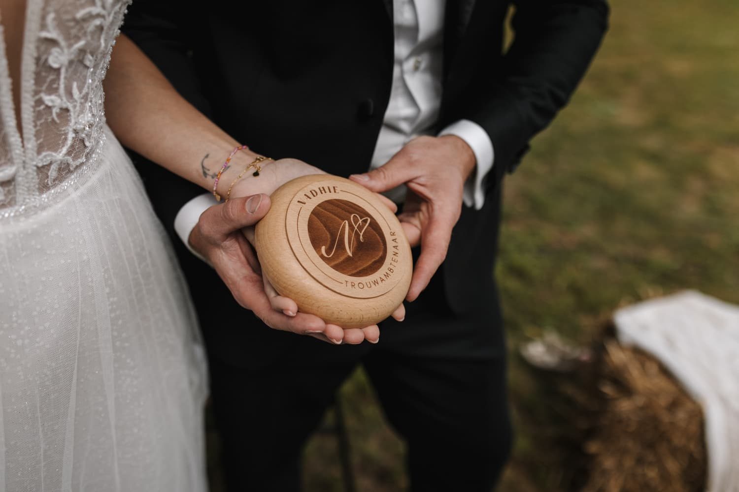 Bruidspaar houdt een houten ringdoosje vast