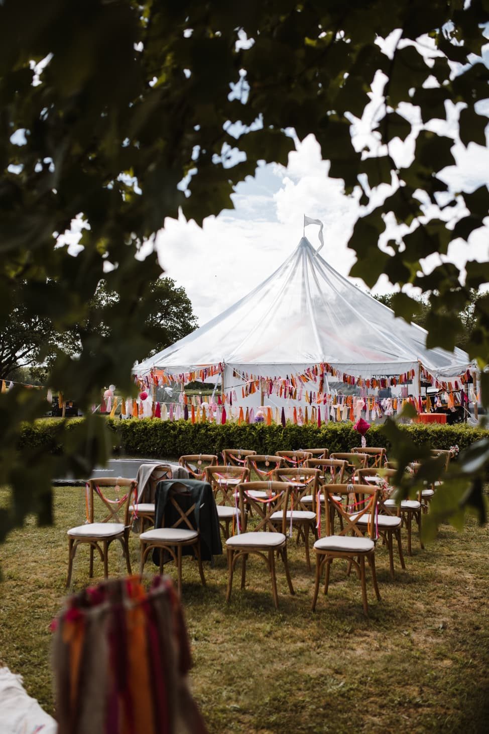 Ceremonieplek met houten stoelen voor een witte tent